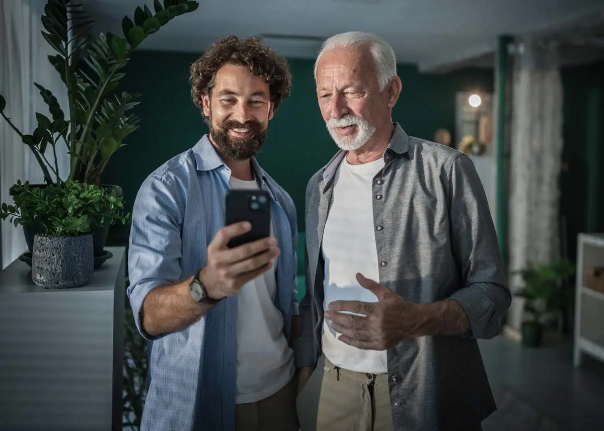 An older man and a younger man looking at a phone together at home